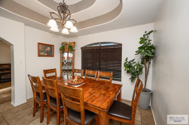 dining space featuring a raised ceiling, light tile patterned flooring, and a chandelier