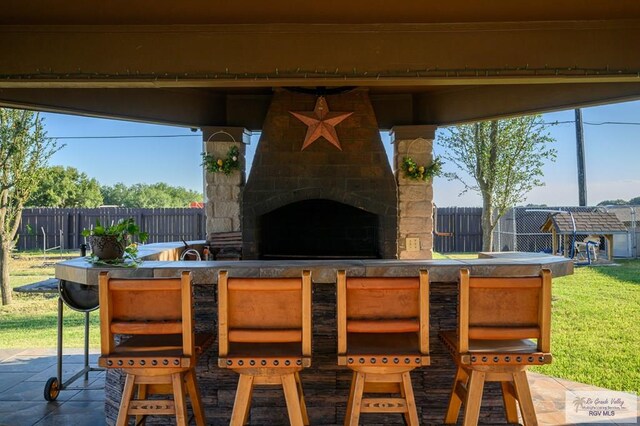 view of patio / terrace with an outdoor stone fireplace and exterior bar