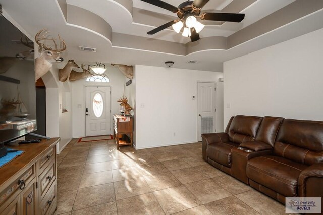 living room featuring a raised ceiling and ceiling fan