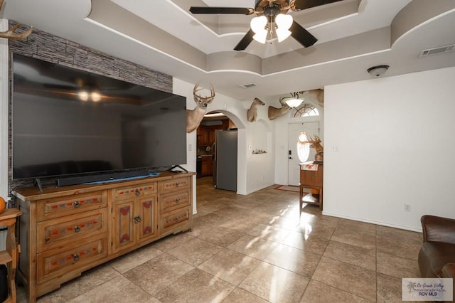 interior space with a tray ceiling, stainless steel refrigerator, and ceiling fan