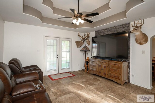 living room with french doors, a raised ceiling, and ceiling fan