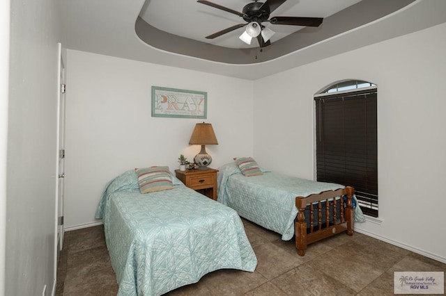 bedroom with ceiling fan and a tray ceiling