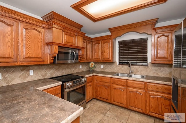 kitchen featuring tasteful backsplash, sink, light tile patterned floors, and stainless steel appliances