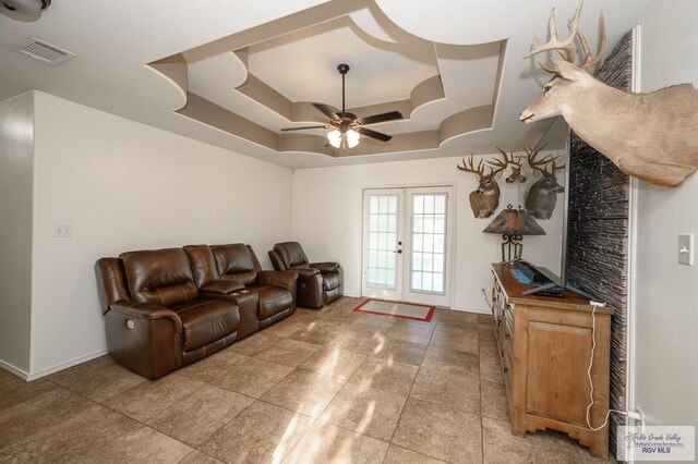 living room featuring french doors, a tray ceiling, and ceiling fan