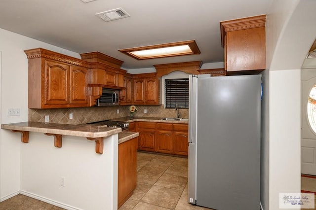 kitchen with sink, stainless steel appliances, a kitchen breakfast bar, tasteful backsplash, and kitchen peninsula