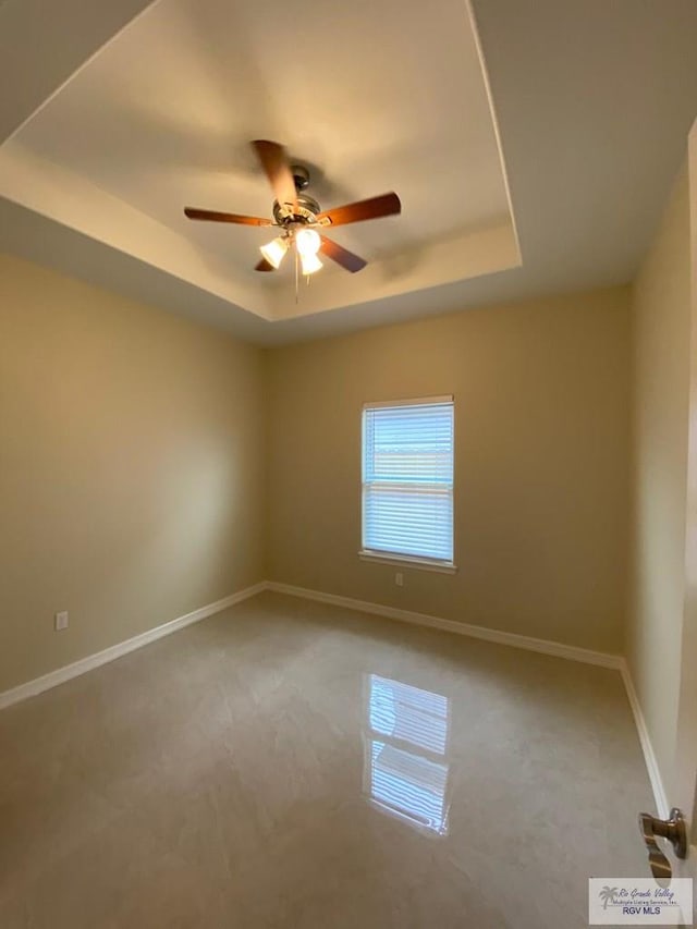 spare room with carpet, ceiling fan, and a raised ceiling