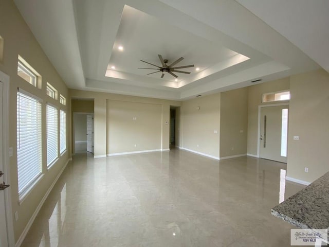 unfurnished room featuring a raised ceiling and ceiling fan