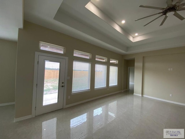 interior space featuring a raised ceiling and ceiling fan