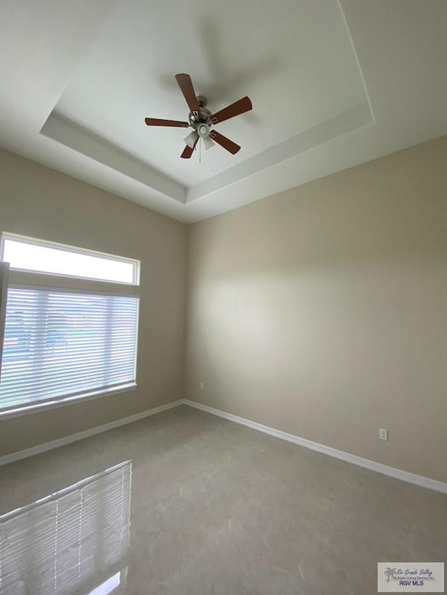 empty room featuring ceiling fan and a tray ceiling