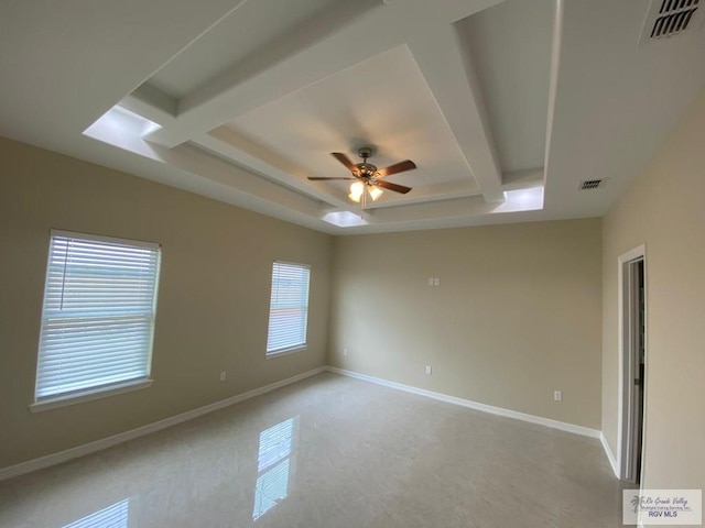 empty room with beam ceiling, a raised ceiling, and ceiling fan