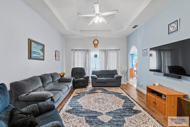 2518 Thomas Ln, Harlingen, TX 78550 - living room featuring arched walkways, wood finished floors, a raised ceiling, a ceiling fan, and baseboards