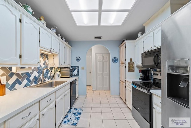 2518 Thomas Ln, Harlingen, TX 78550 - kitchen with stainless steel appliances, a sink, arched walkways, and white cabinetry
