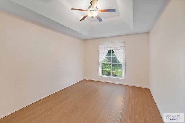 2518 Thomas Ln, Harlingen, TX 78550 - spare room with a tray ceiling, wood finished floors, ceiling fan, and baseboards