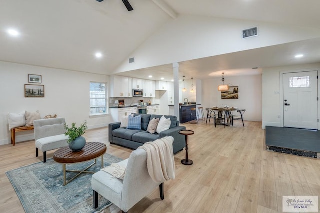 living room featuring beamed ceiling, high vaulted ceiling, and light hardwood / wood-style flooring