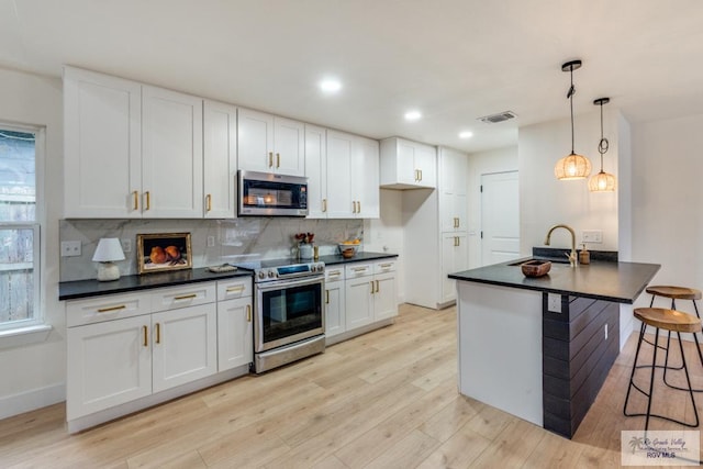 kitchen with decorative light fixtures, white cabinetry, sink, a kitchen breakfast bar, and stainless steel appliances