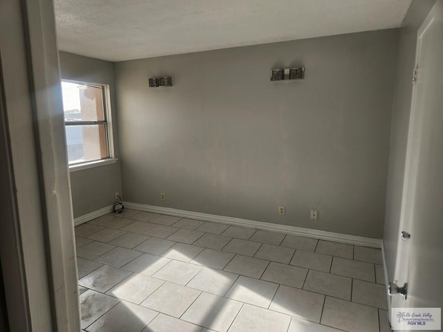 tiled empty room with a textured ceiling