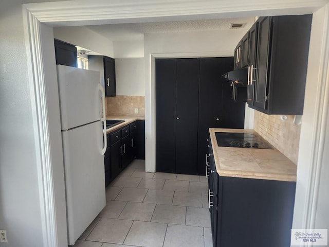 kitchen with decorative backsplash, black electric stovetop, light tile patterned floors, and white refrigerator