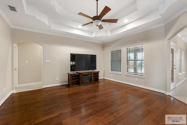 5302 Remington Dr, Harlingen, TX 78552 - unfurnished living room featuring arched walkways, a raised ceiling, wood-type flooring, ceiling fan, and ornamental molding