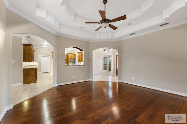 5302 Remington Dr, Harlingen, TX 78552 - unfurnished living room featuring ceiling fan, light wood finished floors, a raised ceiling, arched walkways, and a high ceiling