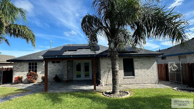 back of house featuring a yard, a patio area, french doors, and solar panels