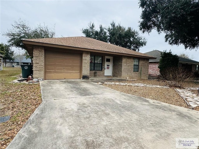 ranch-style home featuring brick siding, concrete driveway, a garage, and roof with shingles