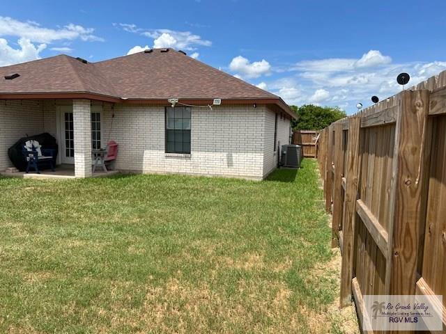 back of house with a yard and central AC