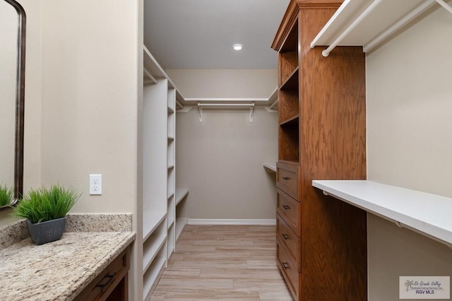 walk in closet with light hardwood / wood-style floors