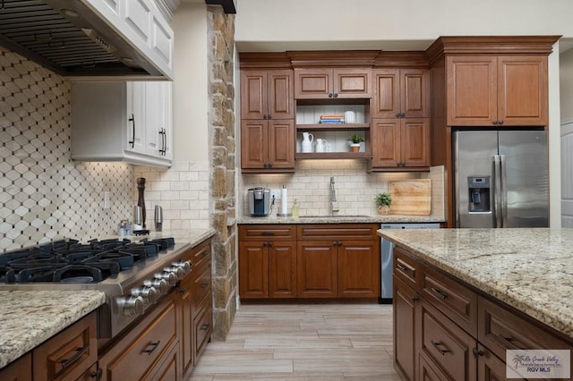 kitchen with decorative backsplash, sink, stainless steel appliances, and range hood