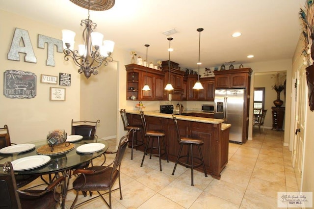 kitchen featuring kitchen peninsula, appliances with stainless steel finishes, an inviting chandelier, and hanging light fixtures