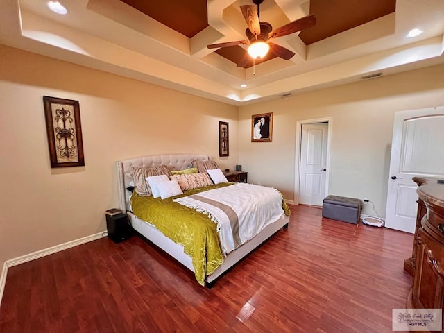 bedroom featuring hardwood / wood-style floors, a tray ceiling, and ceiling fan