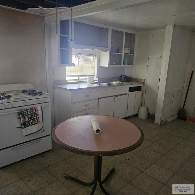 1130 N Sunset Dr, Harlingen, TX 78550 - kitchen with white gas range, open shelves, white cabinetry, and light countertops