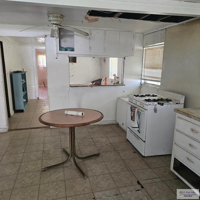 1130 N Sunset Dr, Harlingen, TX 78550 - kitchen with white range with gas stovetop, white cabinetry, plenty of natural light, and a ceiling fan