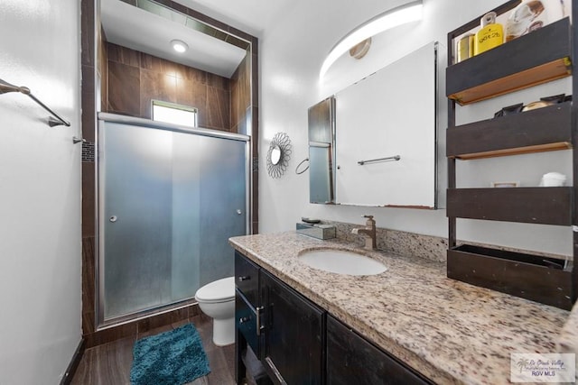 bathroom featuring hardwood / wood-style flooring, vanity, toilet, and a shower with door