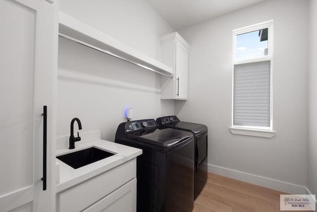 9073 New Orleans Ct, Los Fresnos, TX 78566 - laundry area featuring washing machine and dryer, cabinet space, light wood finished floors, and baseboards