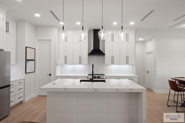 9073 New Orleans Ct, Los Fresnos, TX 78566 - kitchen featuring wall chimney range hood, freestanding refrigerator, backsplash, light wood-type flooring, and recessed lighting