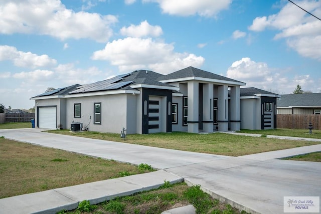 prairie-style home featuring a garage, central AC unit, a front yard, and solar panels