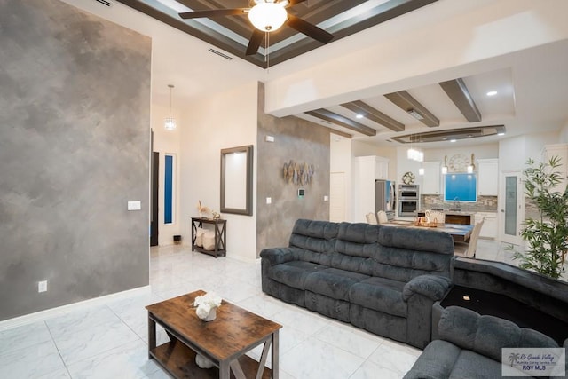 living room featuring beamed ceiling, sink, and ceiling fan