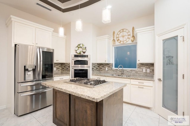 kitchen featuring pendant lighting, sink, white cabinets, a center island, and stainless steel appliances