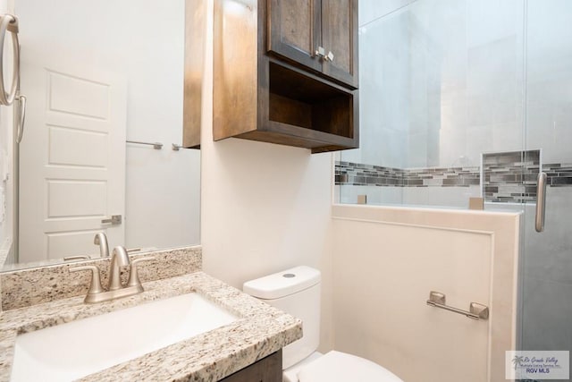 bathroom featuring vanity, a shower with shower door, and toilet