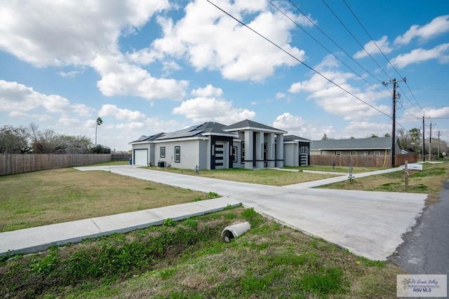 view of front of home with a garage, a front yard, and solar panels