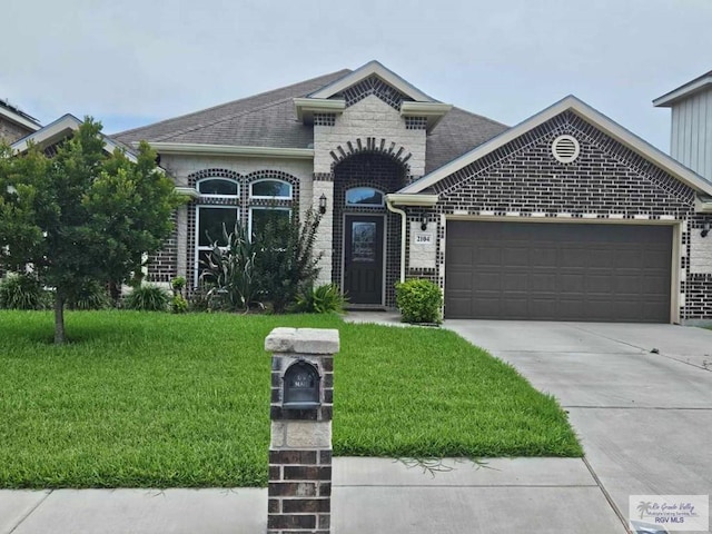 2104 Tomatillo Dr, Weslaco, TX 78596 - french provincial home with a garage, a front lawn, concrete driveway, brick siding, and roof with shingles