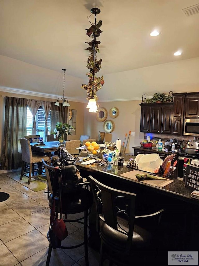 2104 Tomatillo Dr, Weslaco, TX 78596 - kitchen featuring stainless steel appliances, light tile patterned floors, ornamental molding, dark brown cabinets, and tasteful backsplash
