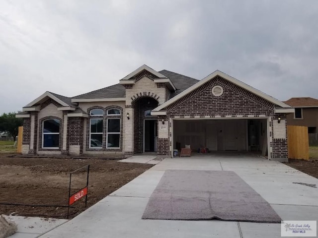 2104 Tomatillo Dr, Weslaco, TX 78596 - french country inspired facade with brick siding, a garage, driveway, and a shingled roof