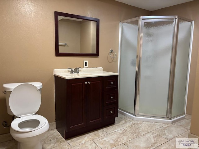 bathroom featuring a shower with door, vanity, and toilet