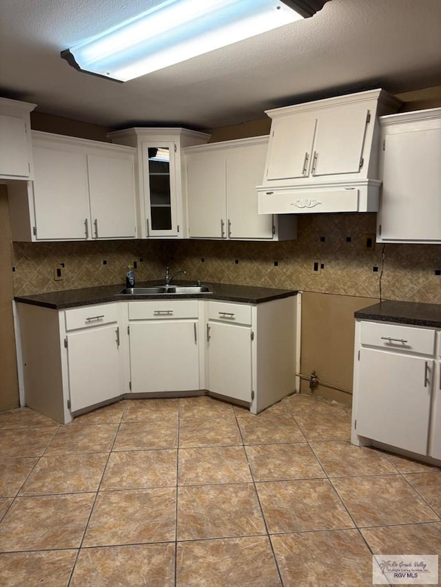 kitchen with white cabinetry, backsplash, sink, and light tile patterned floors