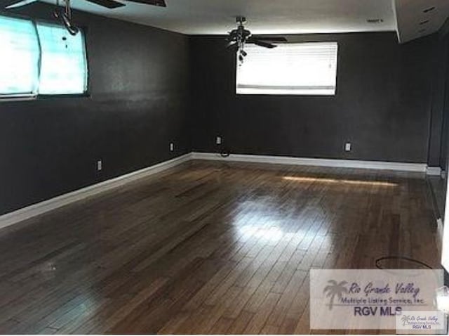 spare room with plenty of natural light, dark wood-type flooring, and ceiling fan