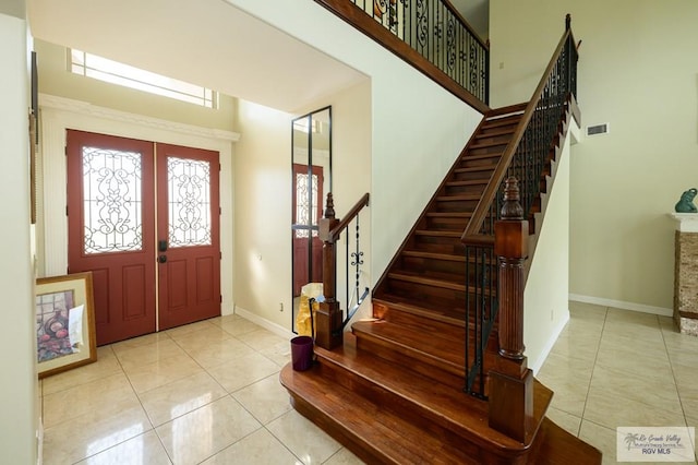 entrance foyer featuring light tile patterned flooring, a towering ceiling, and french doors