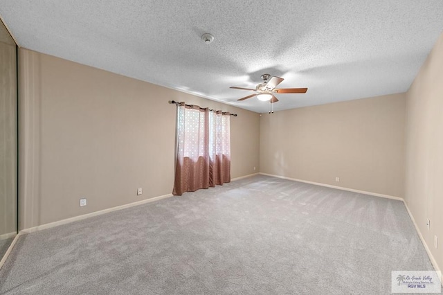 carpeted spare room with a textured ceiling and ceiling fan