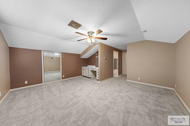 bonus room featuring light carpet, a textured ceiling, ceiling fan, and lofted ceiling