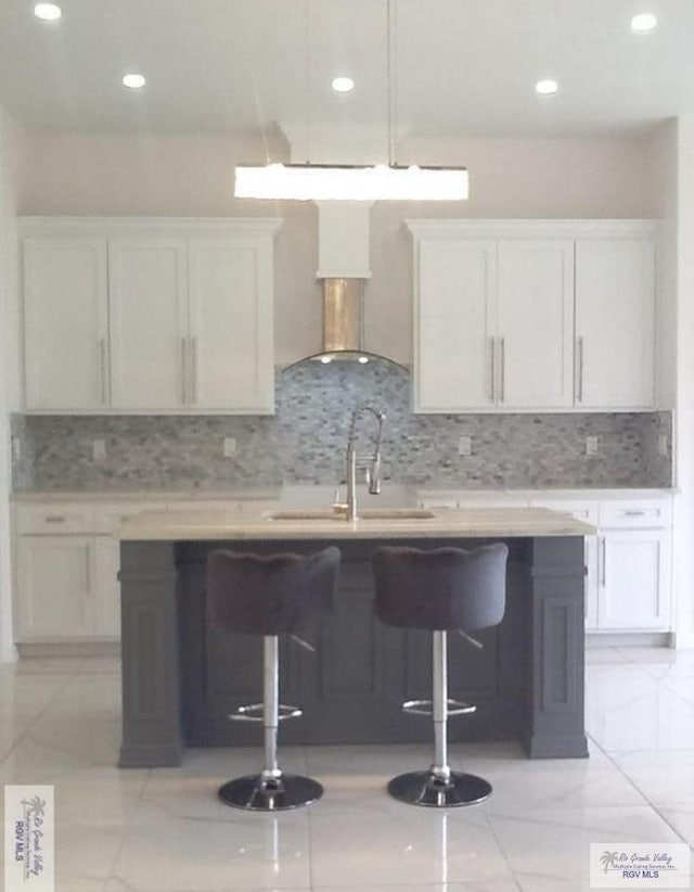 kitchen with white cabinetry, sink, backsplash, and a kitchen breakfast bar